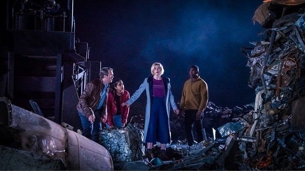 This image shows Team TARDIS--from left to right, Graham O'Brien (played by Bradley Walsh), Yasmin "Yaz" Khan (played by Mandip Gill). the Thirteenth Doctor (played by Jodie Whittaker), and Ryan Sinclair (played by Tosin Cole)--standing amidst a junk field on the junk planet Seffilun 27 in "The Tsuranga Conundrum" (Doctor Who Series 11's fifth episode). The Doctor has paused and looks surprised, having discovered a sonic mine in the detritus. This image shows Team TARDIS--from left to right, Graham O'Brien (played by Bradley Walsh), Yasmin "Yaz" Khan (played by Mandip Gill). the Thirteenth Doctor (played by Jodie Whittaker), and Ryan Sinclair (played by Tosin Cole)--standing amidst a junk field on the junk planet Seffilun 27 in "The Tsuranga Conundrum" (Doctor Who Series 11's fifth episode). The Doctor has paused and looks surprised, having discovered a sonic mine in the detritus.