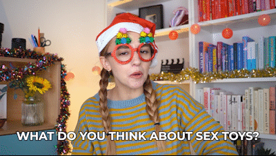 Hannah, wearing silly Christmas glasses, saying, "What do you think about sex toys? Hmm? Hmm? Hmm?"