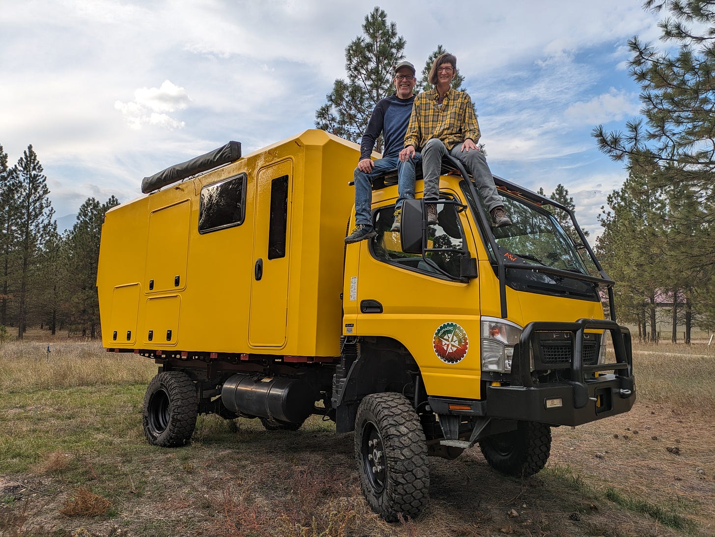 my husband and I sitting atop the cab of a big yellow truck with a camper on the back