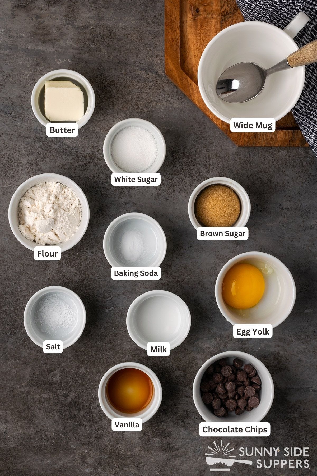 Ingredients for a chocolate chip cookie in a mug in small bowls.