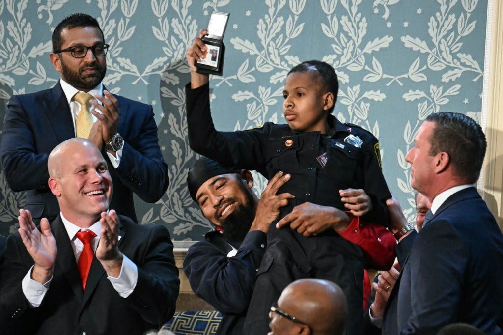 13-year-old cancer survivor Devarjaye "DJ" Daniel is lifted up by his father Theodis Daniel after US President Donald Trump made him an honorary member of the US Secret Service during his address to a joint session of Congress at the US Capitol in Washington, DC, on March 4, 2025. 