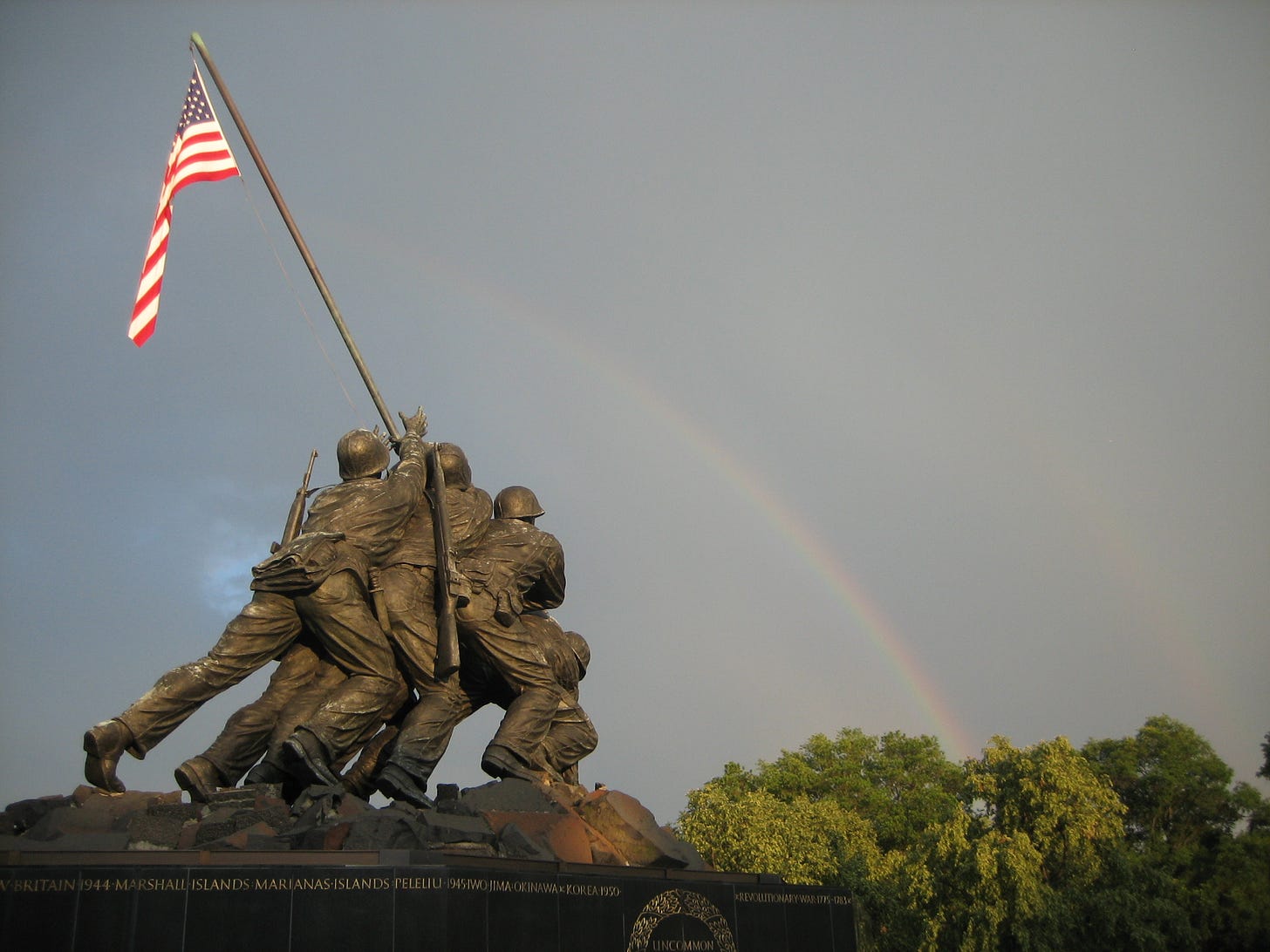 USMC statue with a rainbow in the background.