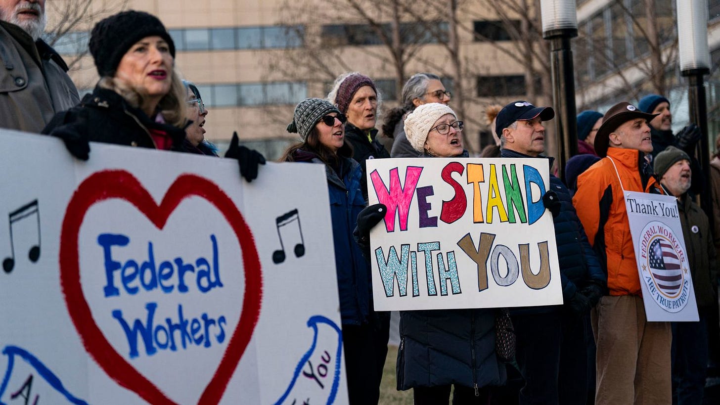 Demonstrators hold signs in support of federal workers outside of the L'Enfant metro station in Washington, DC, on Monday.