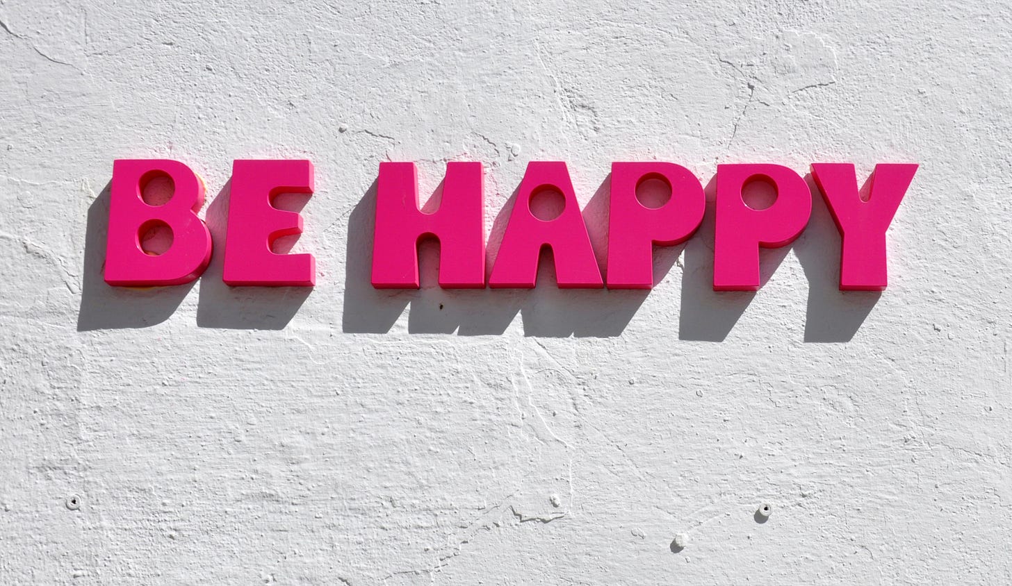 the words "Be happy" on a wall in pink letter