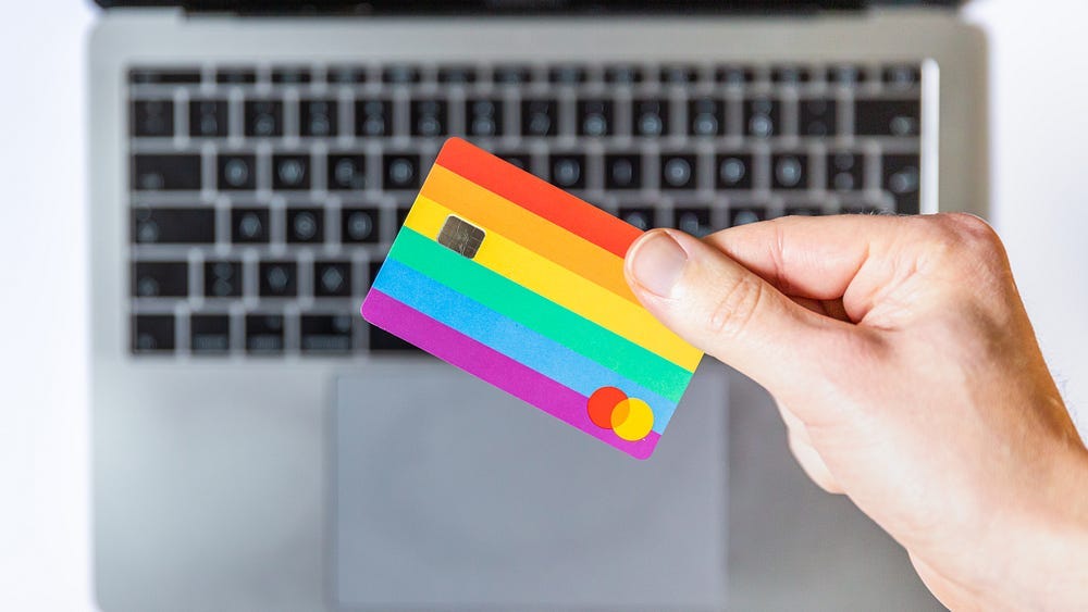 rainbow hued credit card held in front of a keyboard. rainbow hued credit card held in front of a keyboard.