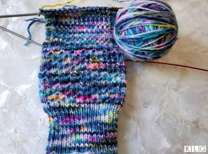 One sock at a time now showing the cuff, leg and the heel flap completed.