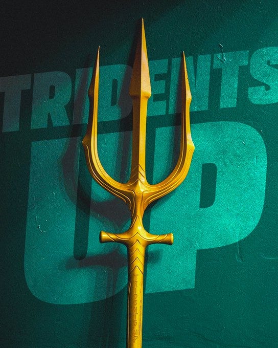Graphic with the trident leaning up against a wall with the words "Tridents up" photoshopped on the same wall. 