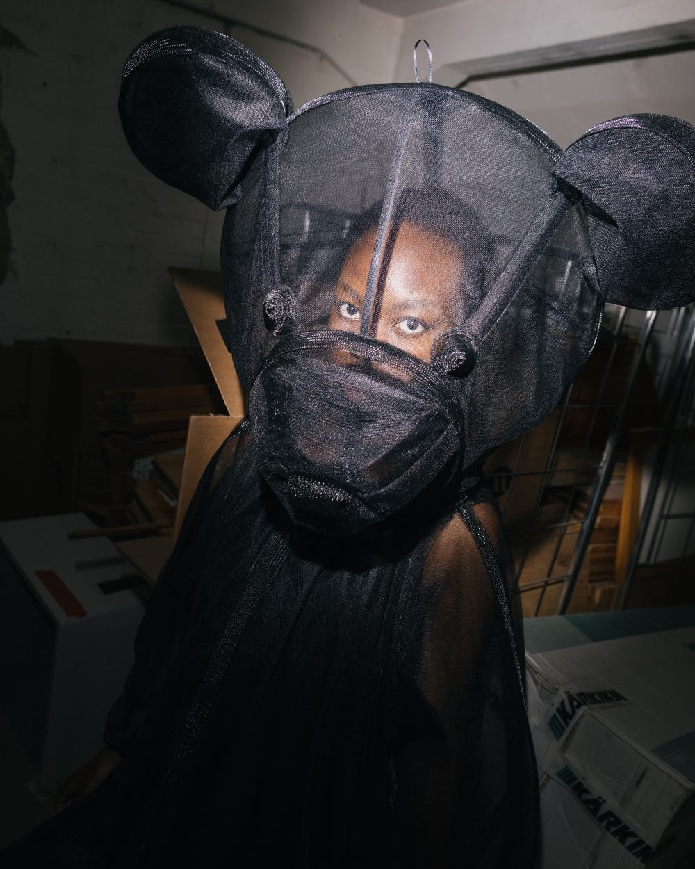 A fashion portrait of a black woman wearing a transparent black teddy bear costume