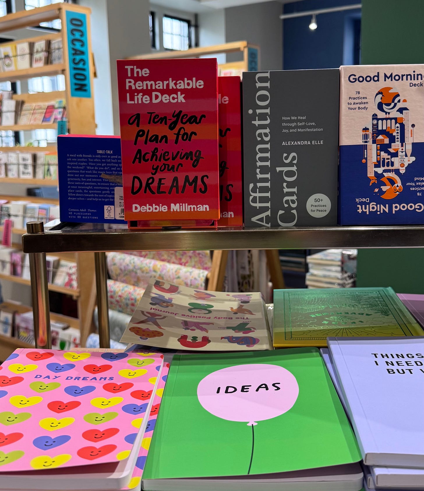 A table of journals and gifts, including "The Remarkable Life Deck: A Ten-Year Plan for Achieving Your Dreams" by Debbie Millman. A table of journals and gifts, including "The Remarkable Life Deck: A Ten-Year Plan for Achieving Your Dreams" by Debbie Millman.