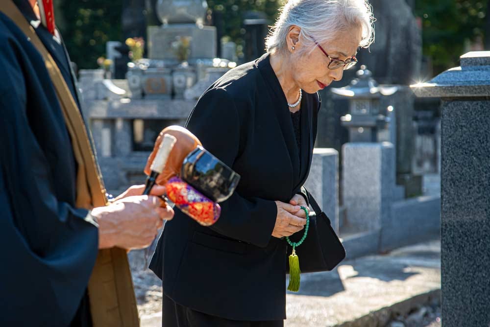 Elder woman paying respects at a grave.