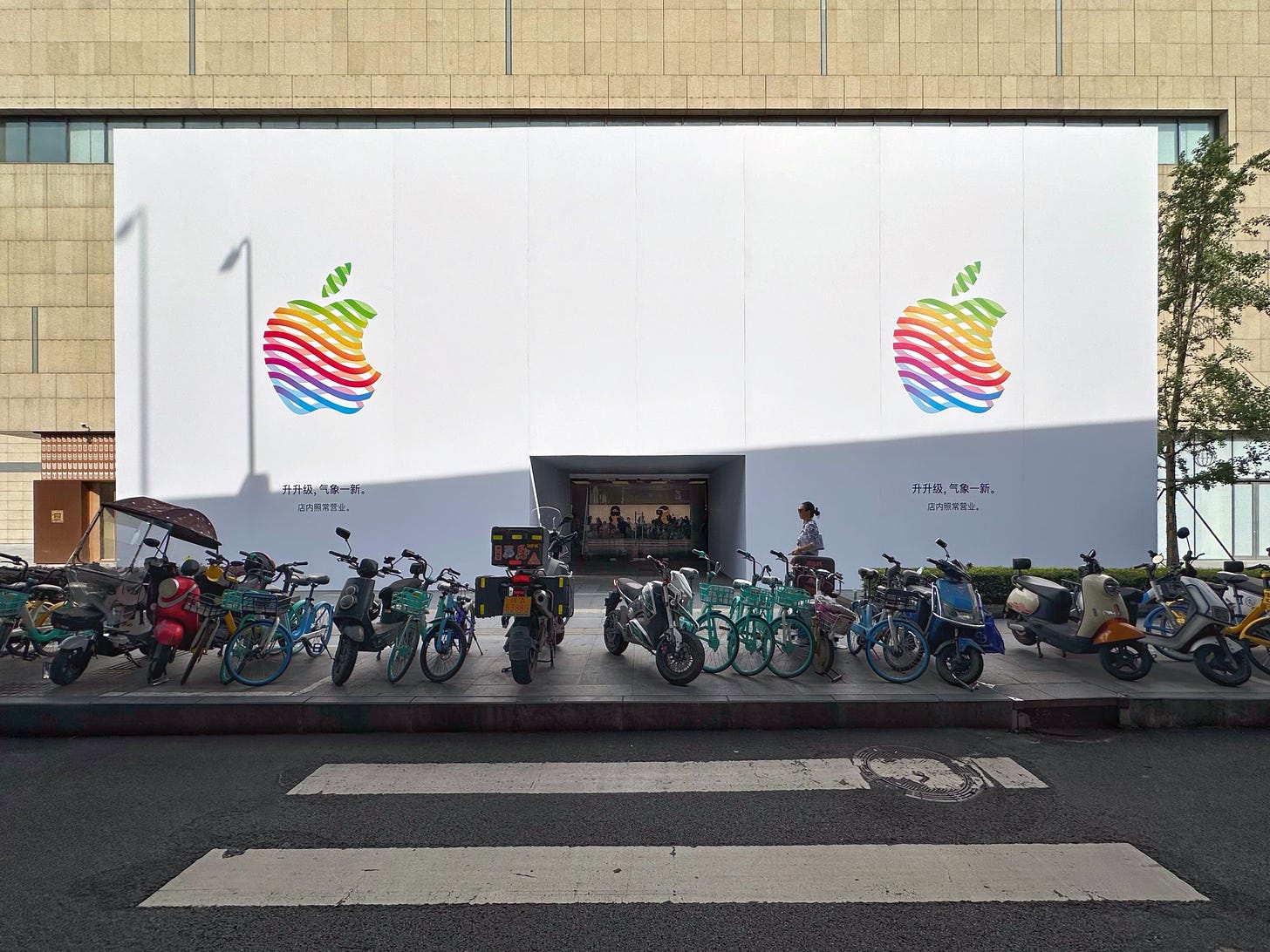 The face of Apple MixC Chengdu in covered with a white temporary wall. On each side of the door is a giant Apple logo in the "heritage" style.