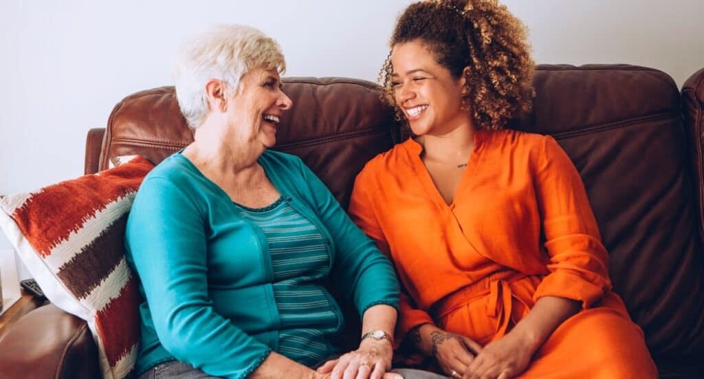 Two women sitting on a sofa smiling