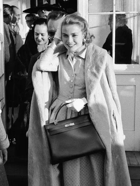 This may contain: black and white photograph of a woman carrying a handbag in front of other people