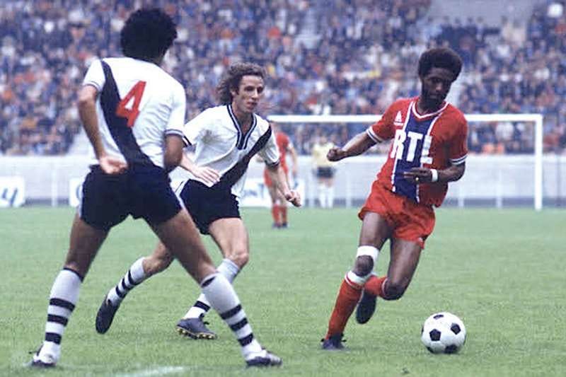 Imagem mostra jogo entre PSG e Vasco da Gama em 1977, onde um jogador do PSG dribla a marcação de um jogador do Vasco enquanto outro o segue 