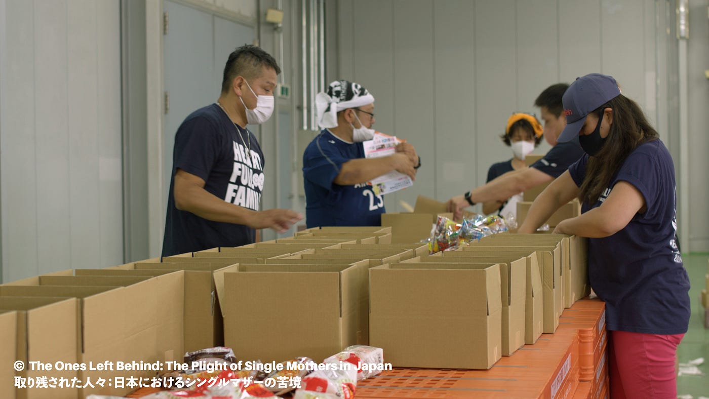 Five individuals in T-shirts packing boxes
