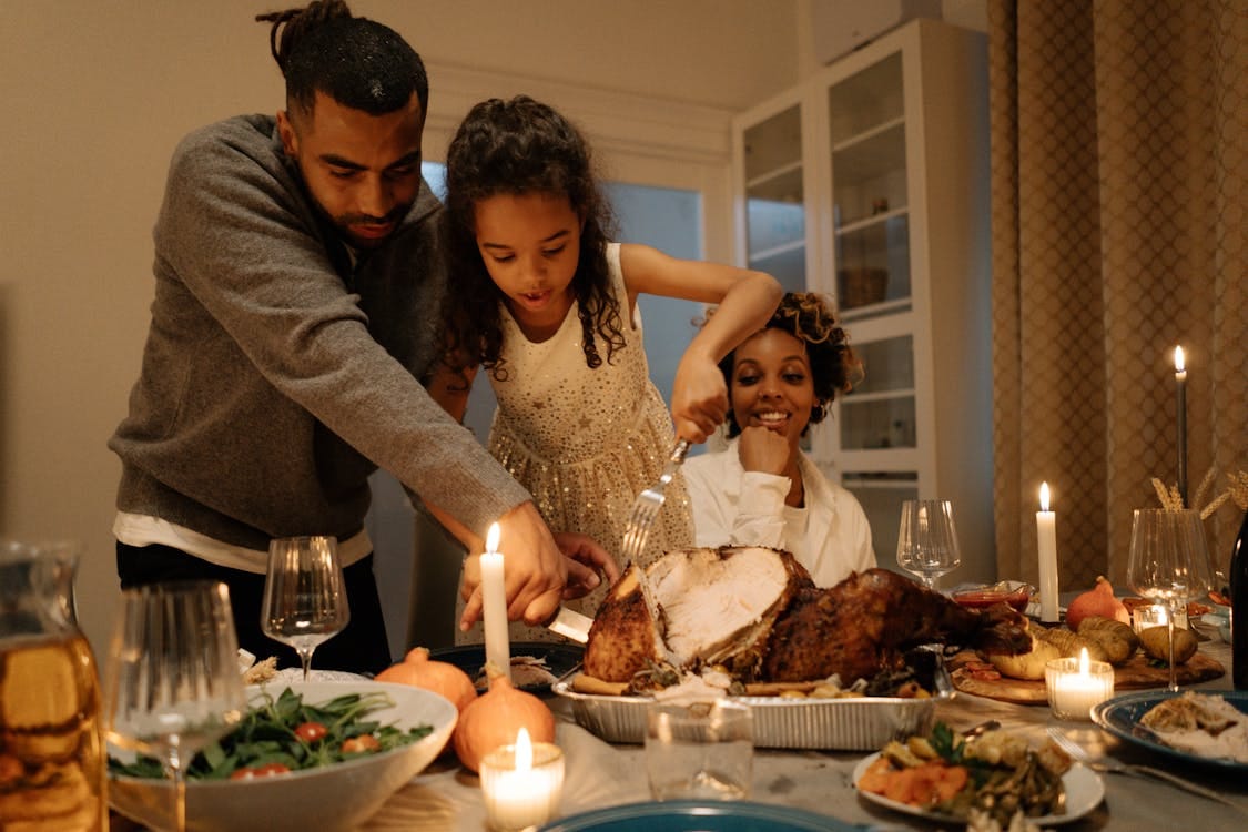 Free A joyful family gathering around a table to celebrate Thanksgiving with a delicious turkey meal. Stock Photo