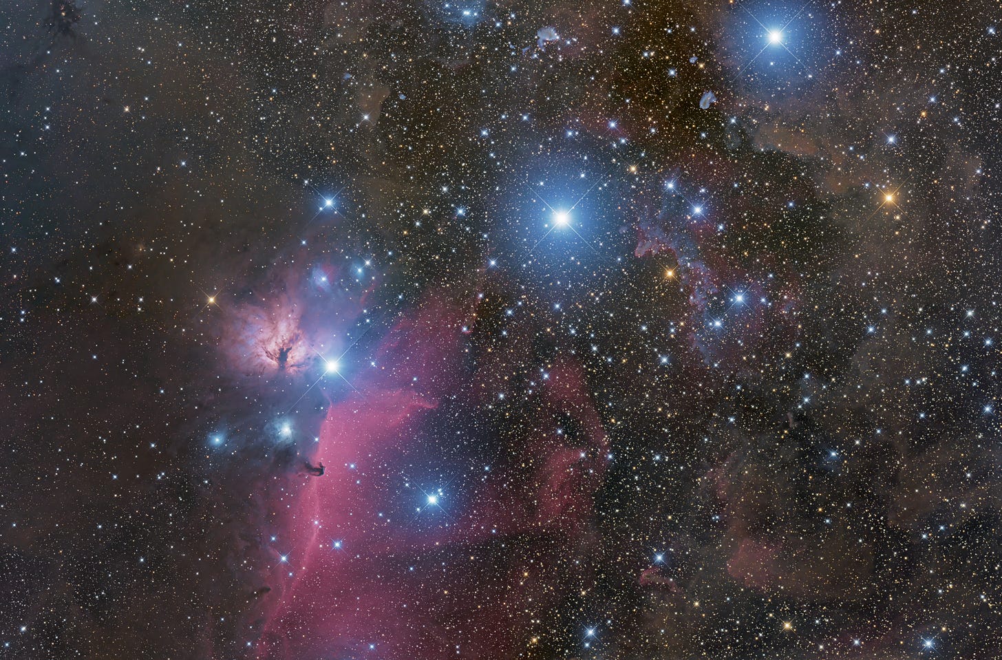 Orion's Belt is shown as three bright stars sitting in a vertical line against the deep black of space, surrounded by other, smaller bright blue stars and clouds of swirling pink gas.