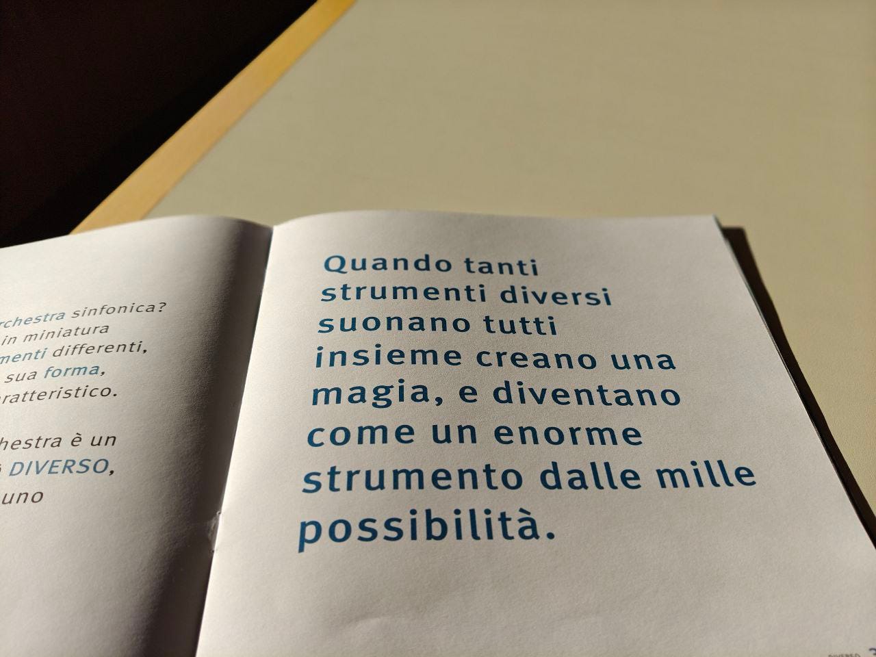 Una pagina della parola Diverso delle Scatoline di effequ, con questa scritta: "Quando tanti strumenti diversi suonano tutti insieme creano una magia, e diventano come un enorme strumento dalle mille possibilità". La pagina è appoggiata su un tavolo di legno bianco sporco e nell'angolino in alto a sinistra si intravede un pezzetto di muro in ombra.