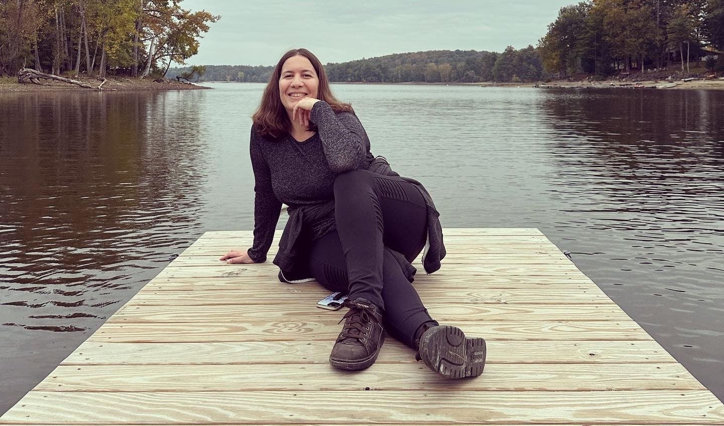 Steph sitting on a pier that juts out over a lake