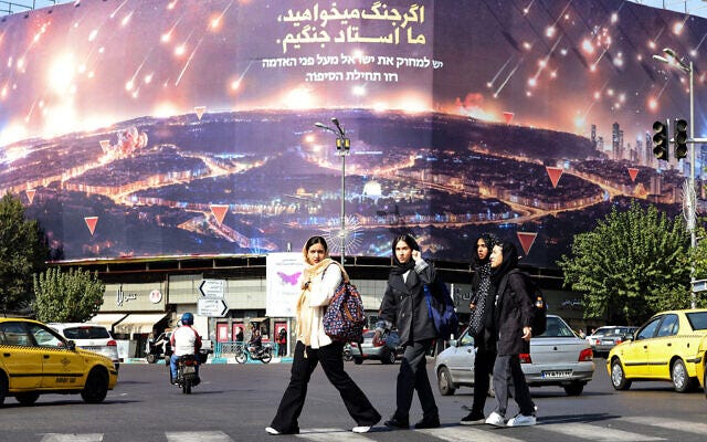 Women walk past an anti-Israel billboard covering the facade of a building in Tehran on October 26, 2024. (Atta Kenare/AFP)