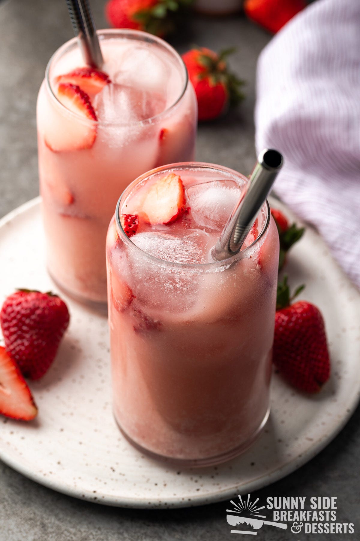 Two pink drinks in glasses with straws.