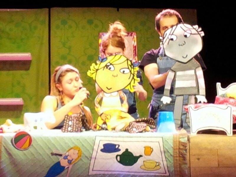 three puppeteers operate two puppets of a girl and a boy. 