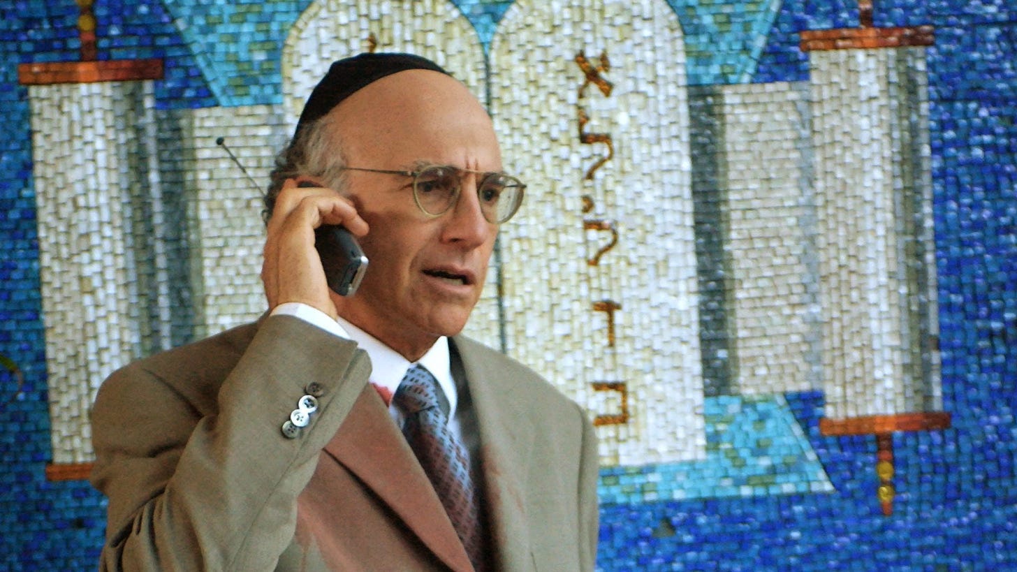 Larry David in front of the ark with a cell phone
