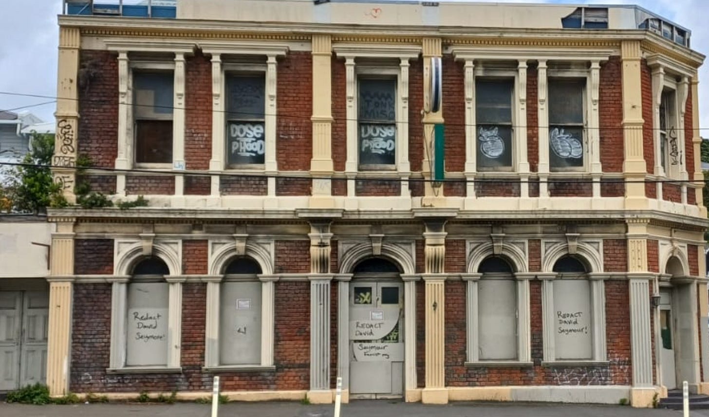 An abandoned building covered in tags saying 'redact David Seymour'