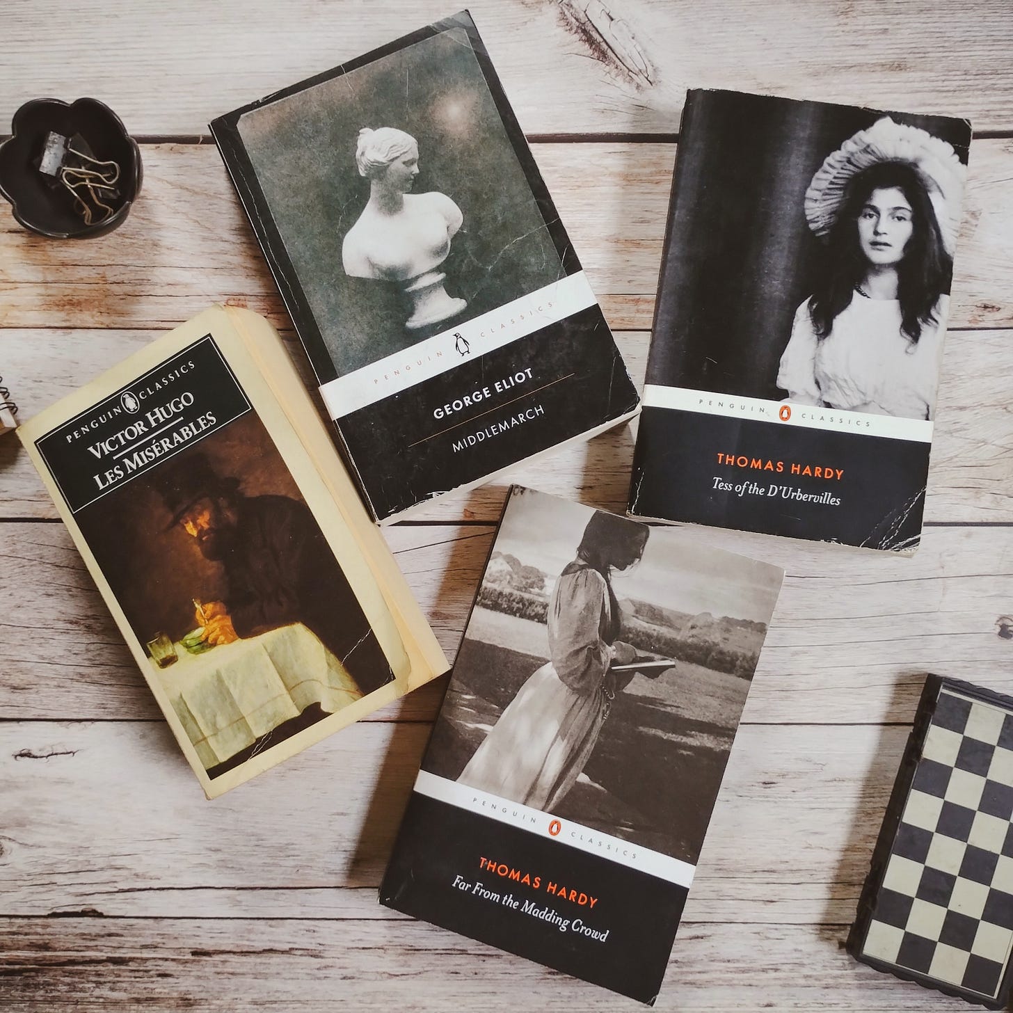 Les Misérables, Victor Hugo, Middlemarch, George Eliot, Far From The Madding Crowd and Tess Of D'urbervilles, Thomas Hardy, Penguin classics editions, on a wooden tabletop