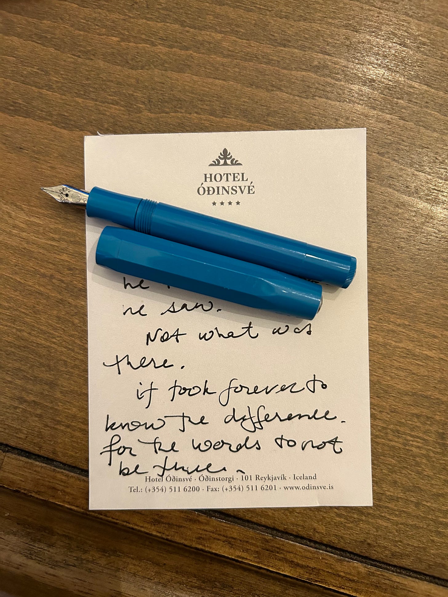 A hotel note pad has scribbled note partially covered by a fountain pen. 