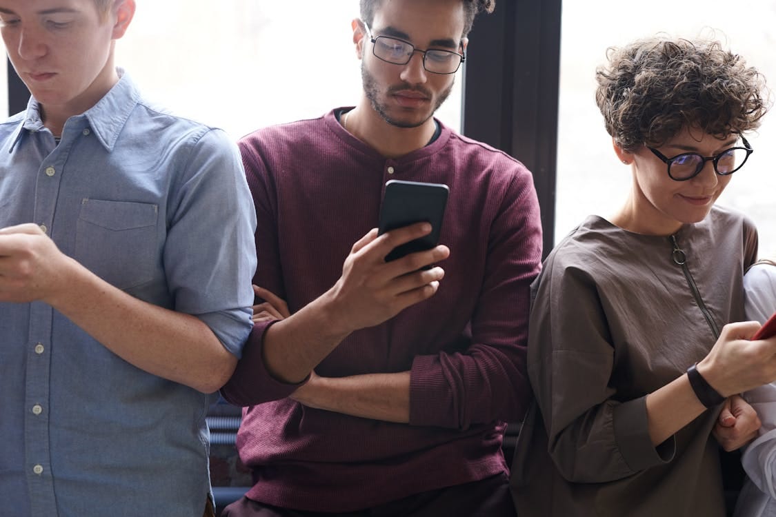 Free A diverse group of people actively using smartphones indoors. Modern technology and social interaction. Stock Photo