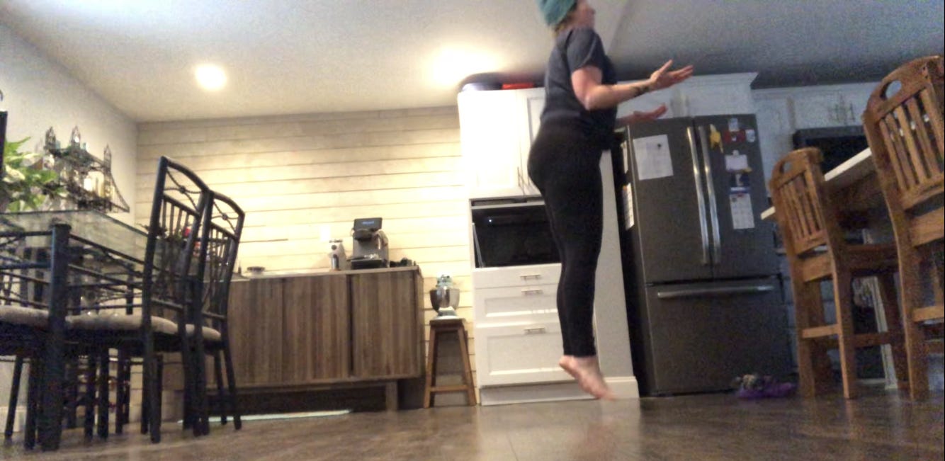A person, mid-jump, in a kitchen.