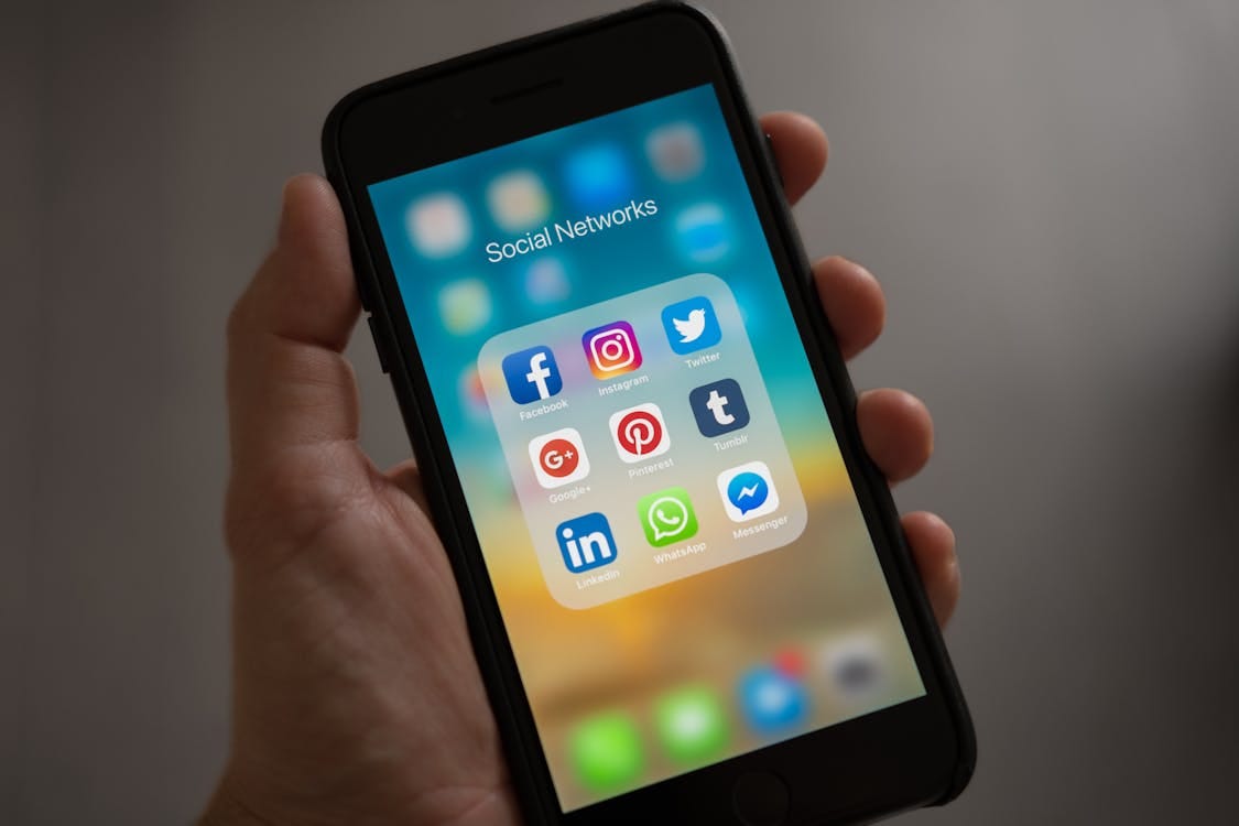Free A smartphone displaying various social media icons held in a hand, showcasing modern communication apps. Stock Photo