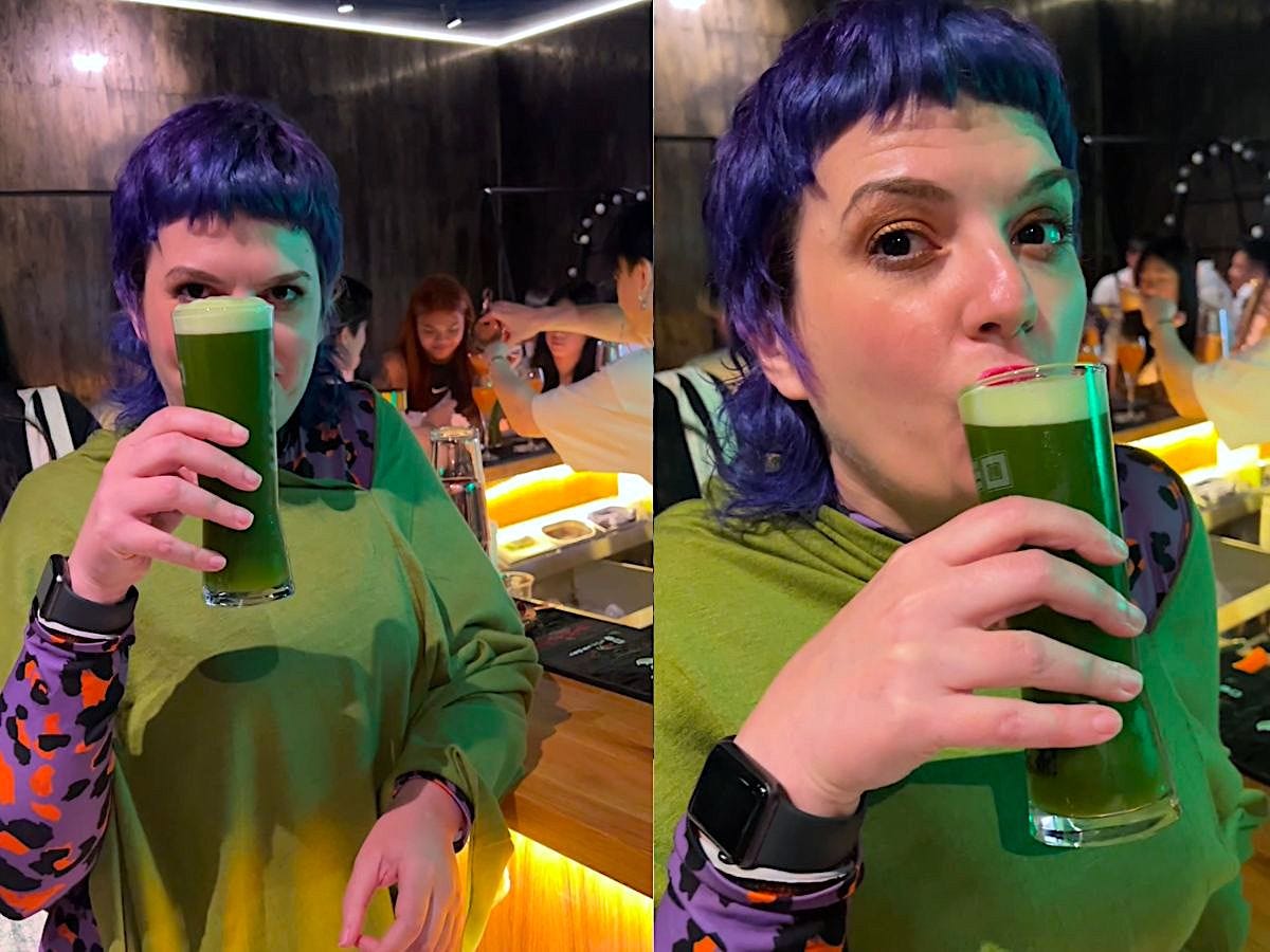 image of a woman with purple hair wearing a purple leopard jumpsuit drinking green matcha beer at monkey trio japanese pub manchester