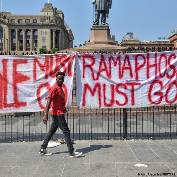 A person walks in front of a banner demanding the resignation of President Cyril Ramaphosa in Pretoria, South Africa