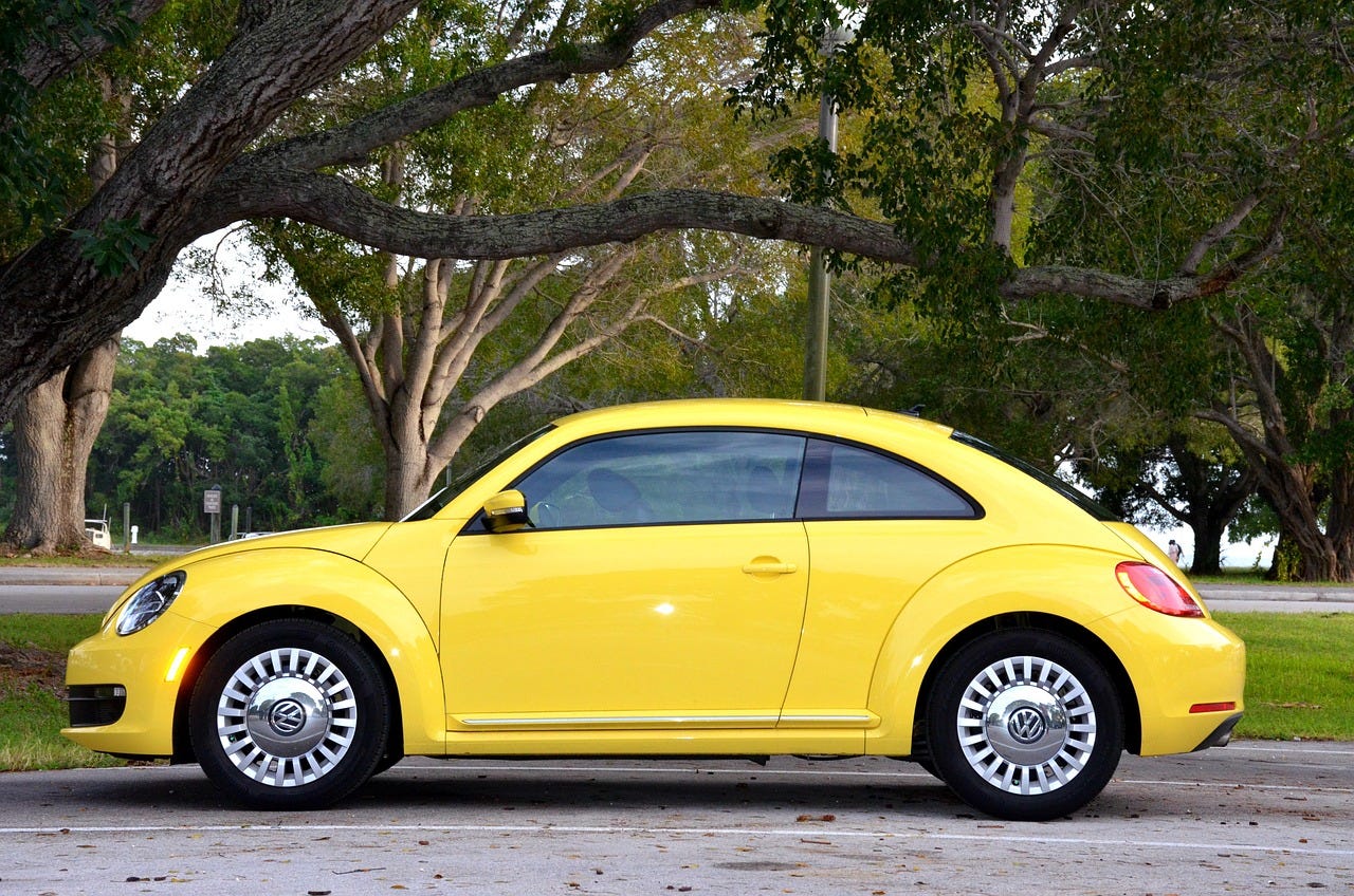 Yellow car parked against a backdrop of trees