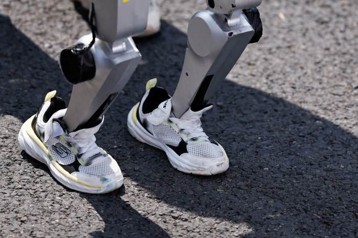 A humanoid robot wearing sneakers at a race.