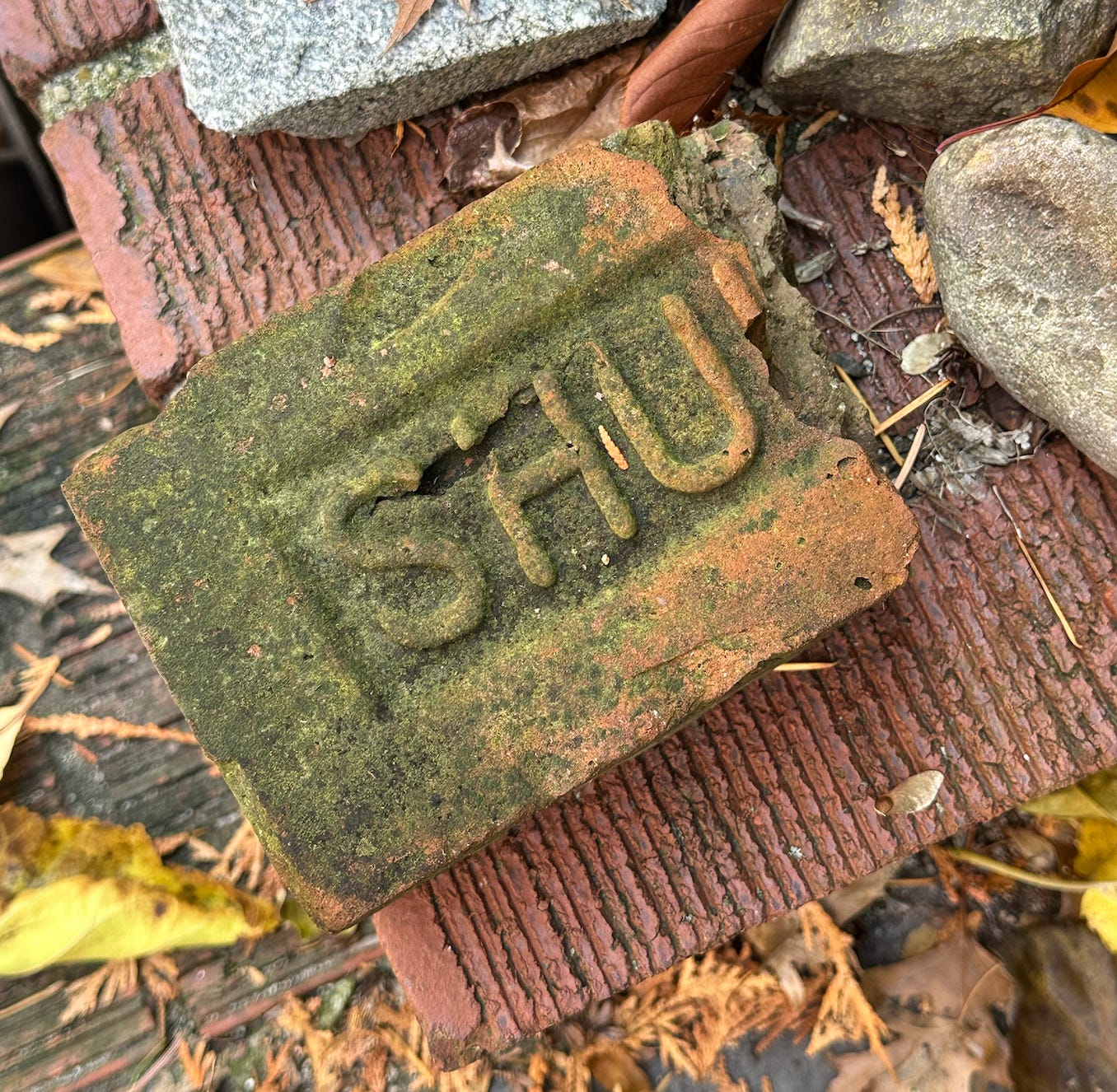 An old broken brick with a patina of moss