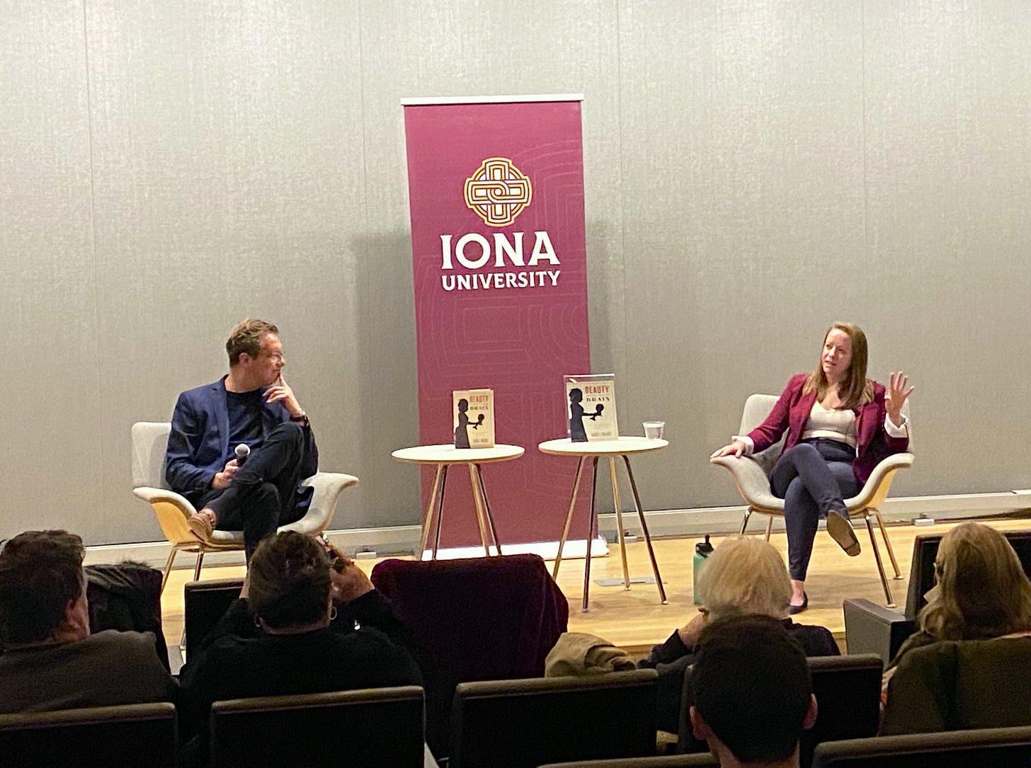 Two speakers on a stage with an Iona banner