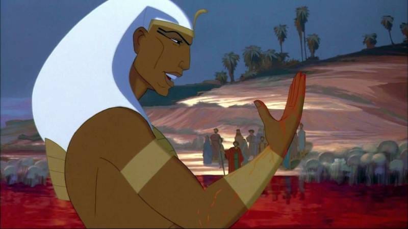 A still from the movie "The Prince of Egypt". Pharaoh stands in the Nile river which has been turned to blood and examines his fingers which he has just dipped in the river.