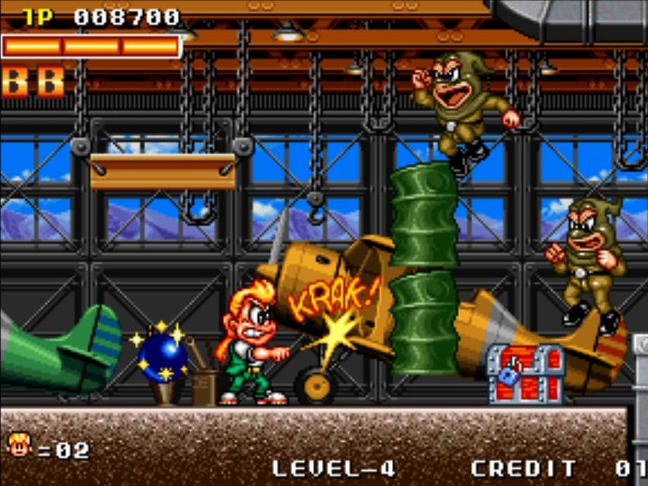 A screenshot from the first stage of Spinmaster, after you've accessed the hangar. Johnny is attacking with his yo-yo, and a "KRAK!" appears to show the sound of the damage it caused to the stack of barrels blocking the path. There's a treasure chest waiting to be opened, as well as two foes, and planes are in the background.