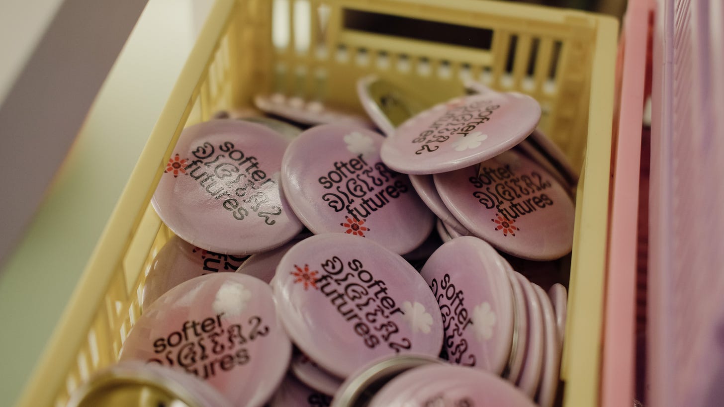Photograph of a basket full of pink badges with 'Softer Digital Futures' written on them
