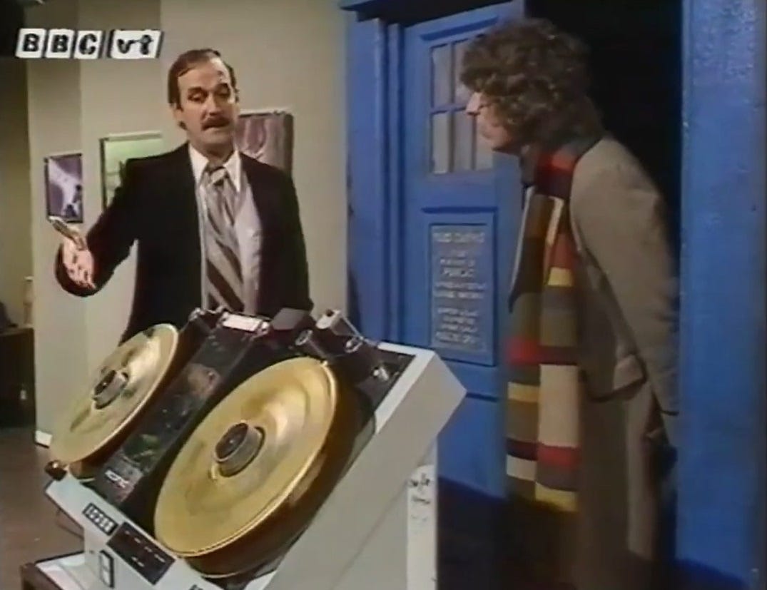 John Cleese delivers a piece of video equipment to Tom Baker in the TARDIS in a skit from 'Good King Memorex'.