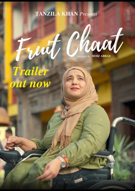 Tanzila, a Pakistani woman with a light skin tone is wearing an olive green long dress with white flowers and a light brown hijab. Sitting in her wheelchair, she has a worried look on her face. Text on the picture says “Tanzila Khan Presents, Fruit Chaat, a film by Moiz Abbas. Trailer out now.