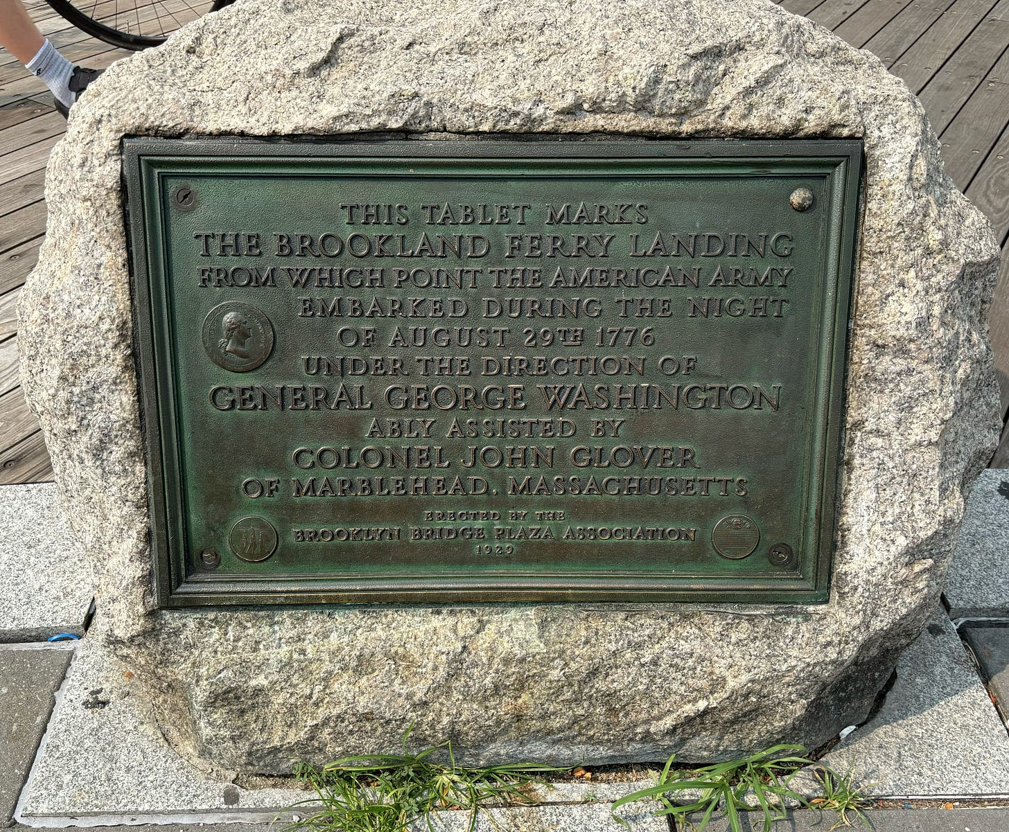 A large stone with a metal plaque embedded. It reads: This tablet marks the Brookland Ferry Landing from which point the American Army embarked during the night of August 29th, 1776 under the direction of General George Washington ably assisted by Colonel John Glover of Marblehead, Massachusetts.