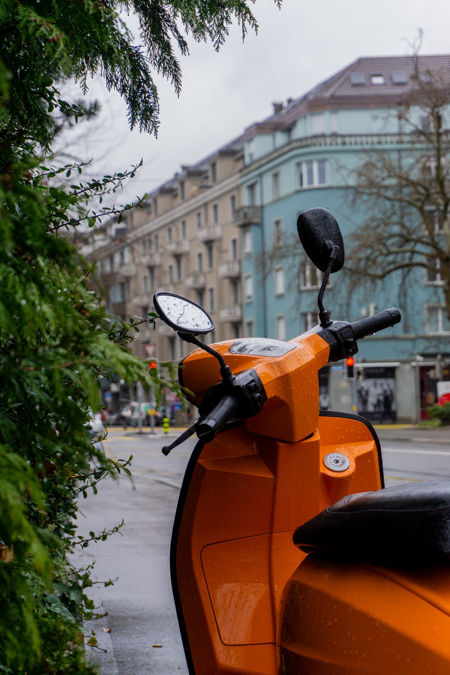 An orange moped in front of a blue building