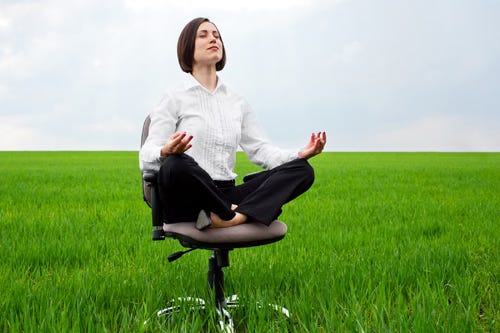 Woman meditating on a desk chair in a meadow