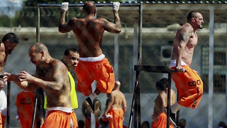 prisoners in orange shorts weight training and exercising