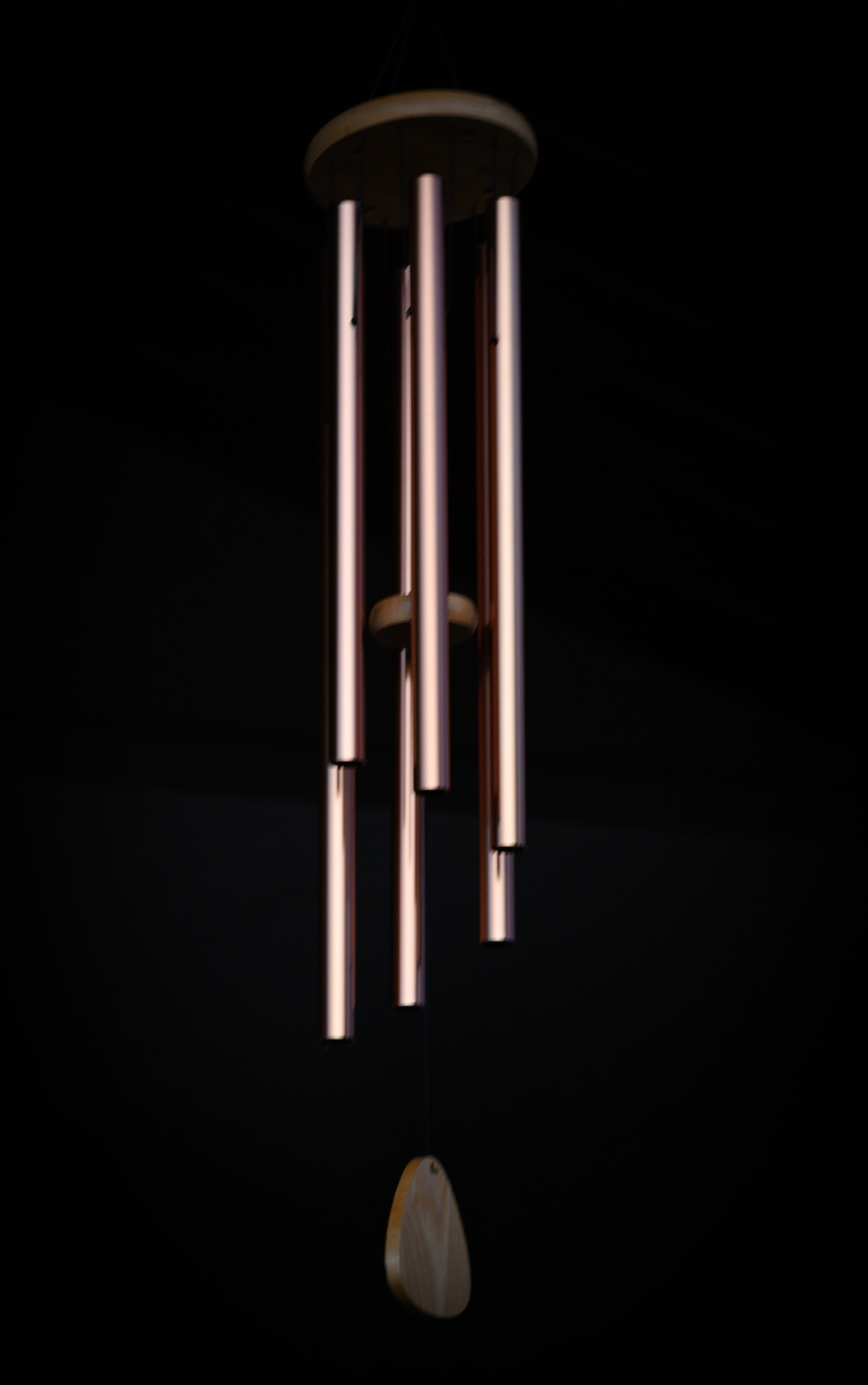 A set of brass chimes hanging against a darkened background