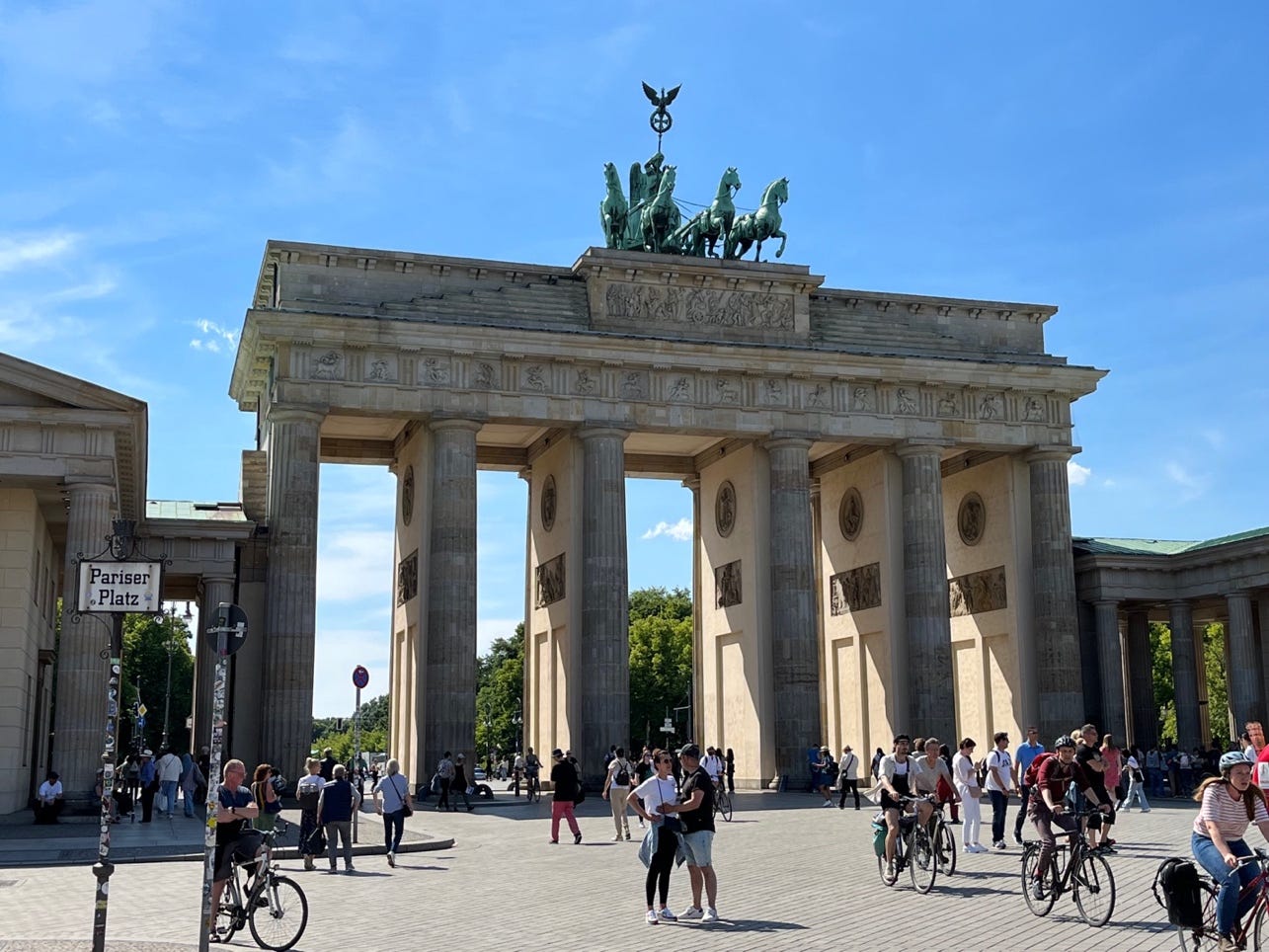 A group of people walking around a large stone structure with Brandenburg Gate in the background

Description automatically generated